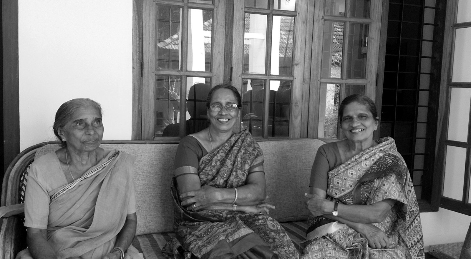 The three sisters seated together on a sofa in the tharavadu